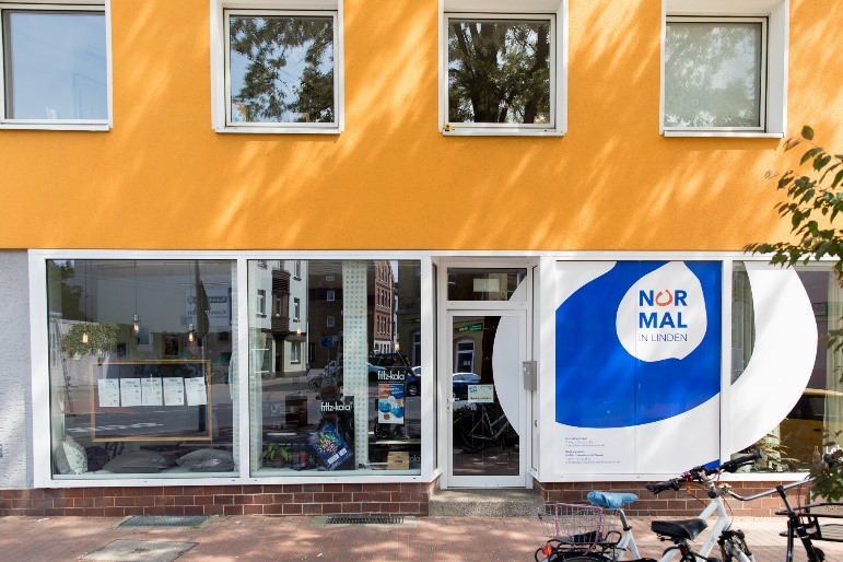 Bildbeschreibung: Man sieht die gesamte Fensterfront des NiL mit dem Eingang und dem Logo des NiL.